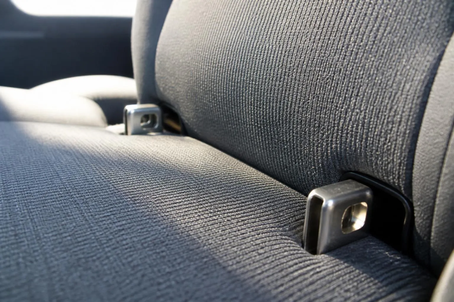 Ancrages ISOFIX métalliques visibles entre l'assise et le dossier d'une banquette arrière